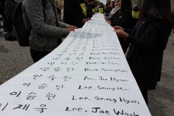 <세월호 참사 1주기를 맞아 18일 오후(현지시간) 독일 베를린 브란덴부르크문 앞에서 열린 희생자 추모집회에서 참석자들은 희생자들의 한글과 영문 이름을 적어넣은 15ｍ 길이의 긴 종이를 펼쳐 이름을 불렀다. | 연합뉴스
