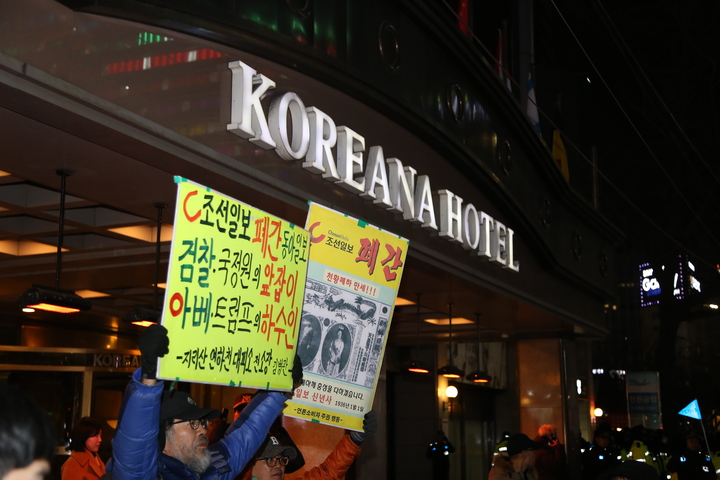 11일 열린 '2020 광화문 탈환 촛불문화제' 행진을 마친 시민들이 코리아나 호텔 앞에서 조선일보의 친일 행각을 비판하는 피켓을 들고 있다.