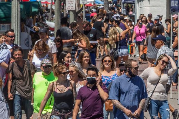 사진: 19일 미국 캘리포니아 주 헌팅턴 비치에서 시민들 대부분이 마스크를 쓰지 않은 채 밀착해서 걷고 있다. ⓒ AFP 연합뉴스