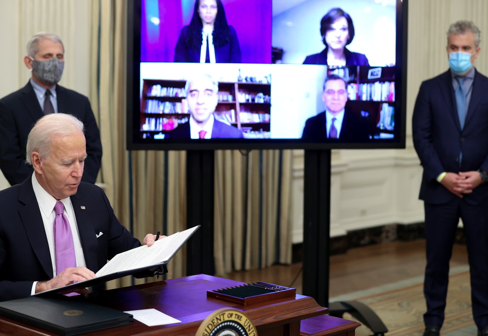 사진: 코로나19 행정명령에 서명하는 바이든 미국 대통령 =조 바이든 미국 대통령이 21일(현지시간) 백악관에서 앤서니 파우치 국립알레르기·전염병연구소 소장(왼쪽)이 지켜보는 가운데 코로나19 대응에 관한 행정명령에 서명하고 있다.