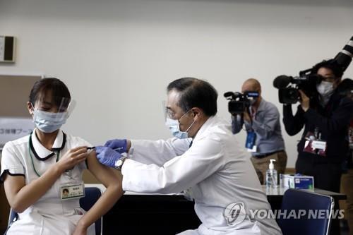 사진: 일본이 신종 코로나바이러스 감염증 백신 접종을 시작한 지난달 17일 도쿄에서 한 의료종사자(왼쪽)가 백신을 접종받고 있다.