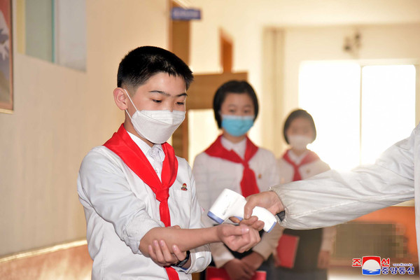 북한 평양 낙랑구역 충성초급중학교 복도에서 지난 5월 신종코로나바이러스 감염증(코로나19) 방역 지침에 따라 마스크를 쓴 학생들의 체온을 측정하고 있다. [조선중앙통신]