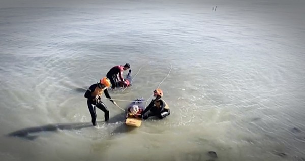 태안해경 구조대원들이 갯보드를 이용해 밀물에 갇힌 고립자 2명을 뭍으로 구조해 내고 있다.(사진=태안해양경찰서)