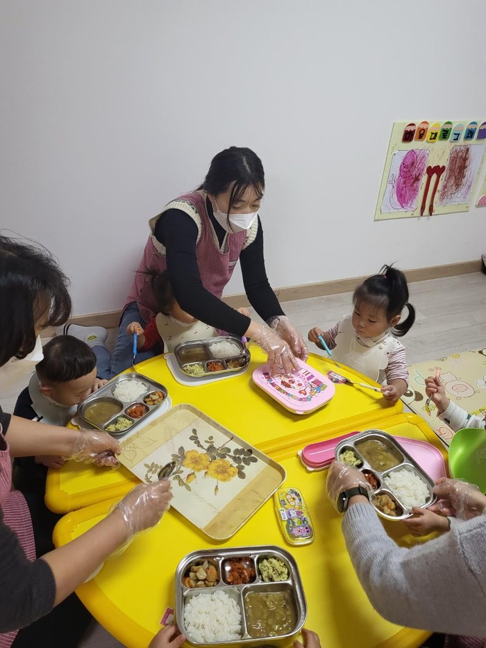 어린이집에서 보육교사의 도움으로 식사를 하고 있는 영·유아들
