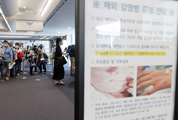 지난 5월 27일 오전 인천국제공항 제1터미널 입국장에 해외입국자들이 검역을 받기 위해 대기하고 있다. 승객들 앞에는 원숭이두창 관련 안내문이 세워져 있다.