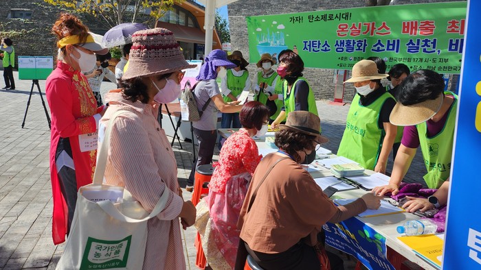 탄소중립 실천 서명을 하고 있는 관광객과 순천시민, 캠페인을 펼치고 있는 한국부인회 전남지부 회원들