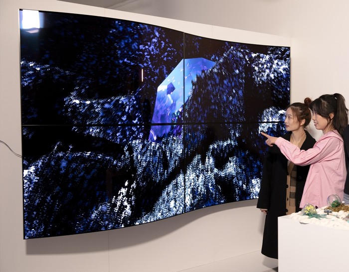 관람객들이 LG디스플레이의 55인치 커브드 OLED 패널 4대를 상하좌우로 이어붙여 만든 작품 '보이지 않는 혁신'(Invisible Reinvention)을 감상하고 있다. (사진=LG디스플레이)