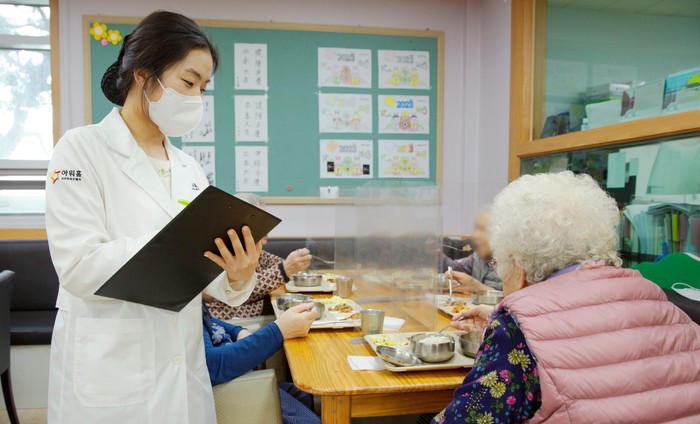 아워홈 영양사가 서울 마포구 한서데이케어센터에서 인지기능개선 관리 식단을 시설 이용 어르신에게 소개하고 있다. (사진=아워홈)