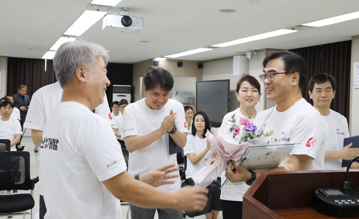 한전산업개발 함흥규 사장이 2050 프렌즈 단장(김인섭 경영처장)에게 꽃다발을 수여한 후 축하인사를 전하고 있다.(사진=한전산업개발)