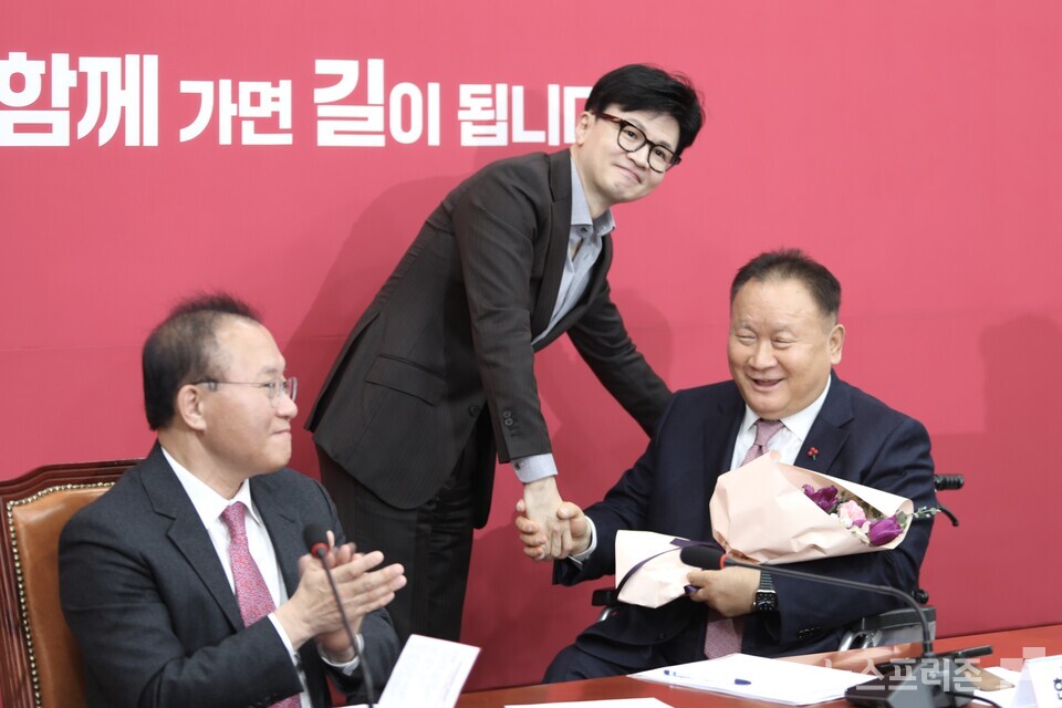 한동훈 국민의힘 비상대책위원장(가운데)이 8일 국회에서 열린 비상대책위원회 회의에서 국민의힘에 입당한 이상민 의원에게 꽃다발을 전달하고 악수하고 있다. (사진=김정현 기자)