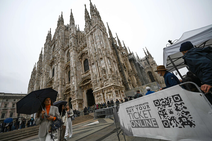 이탈리아 밀란의 두오모 성당 앞에서 지난 25일 성당 입장권을 살 수 있는 QR코드 배너 주변으로 관광객들이 지나고 있다.  (사진=AFP 연합뉴스)