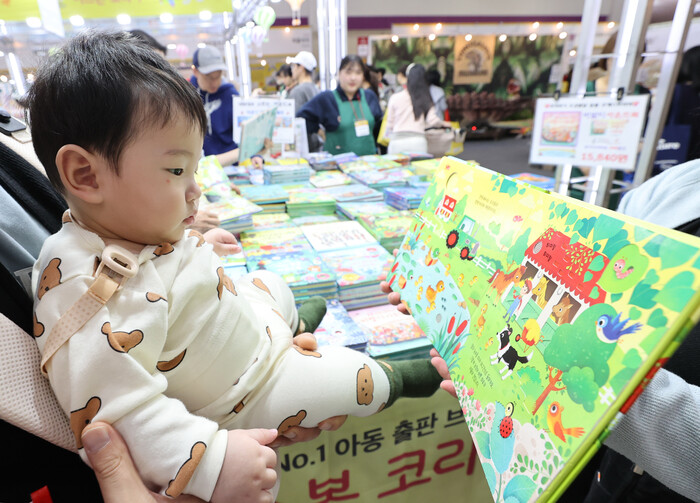 지난 14일 엄마와 함께 서울국제유아교육전을 찾은 한 아기가 그림책을 보고 있다. (사진=연합뉴스)