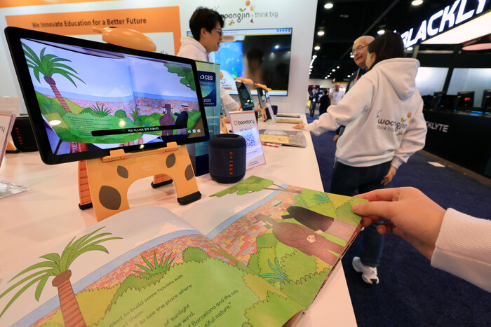 CES 2025 웅진씽크빅 전시관에서 7일(현지시각) 관람객이 생성 AI 기술을 적용해 책을 원하는 언어로 읽어주는 독서 플랫폼 '북스토리'를 살펴보고 있다. (사진=연합뉴스)
