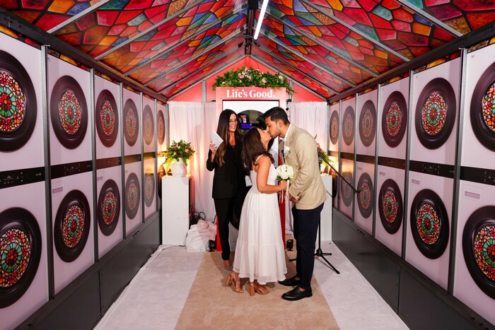 LG전자가 사연 공모로 뽑은 한쌍의 연인이 미국 뉴욕 하이라인 파크에서 결혼서약을 한 뒤 입맞추고 있다. 연인들 양 옆으로 스테인드 글라스로 장식된 워시타워가 놓여 있다. (사진=LG전자 제공)