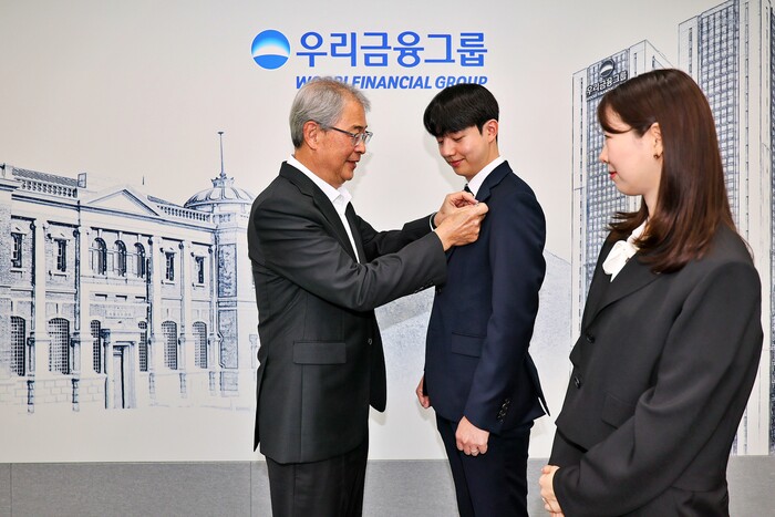 우리금융그룹 임종룡 회장이 1일 그룹의 새 가족이 된 동양생명·ABL생명 직원에게 디지털 선도의 의미가 담긴 새로운 그룹 보조휘장을 달아주고 있다. (사진=우리금융)