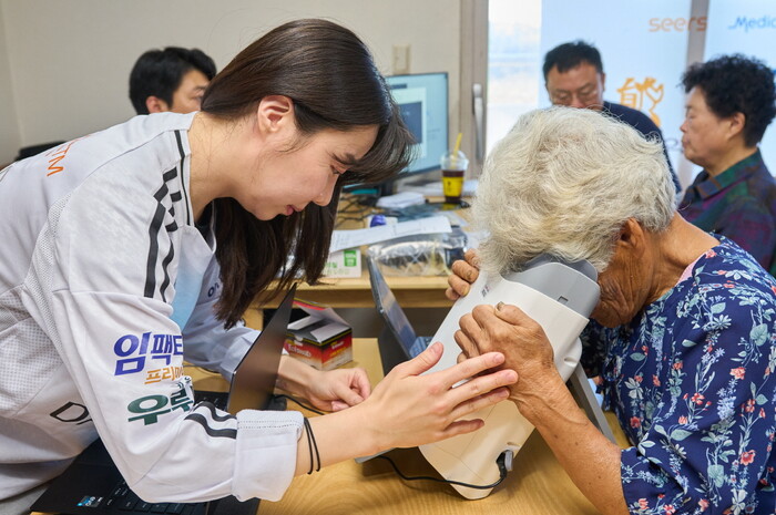 대부도 주민(앞줄 오른쪽)이 AI 실명질환 진단 설루션 ‘위스키’와 안저카메라 ‘옵티나 제네시스’를 이용해 안저 상태를 확인하고 있다. (사진=대웅제약 제공)