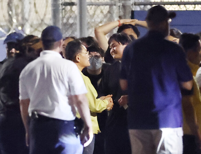 이민단속으로 체포됐던 현대차-LG엔솔 배터리공장 건설 현장 직원들이 11일(현지시각) 미국 조지아주 포크스턴의 이민세관단속국(ICE) 구금시설에서 나오며 조기중 워싱턴 총영사(노란 옷 안경 쓴 이)와 손을 잡고 이야기하고 있다. (사진=연합뉴스)
